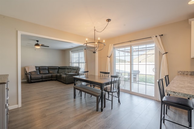 dining area with ceiling fan with notable chandelier, wood finished floors, and baseboards