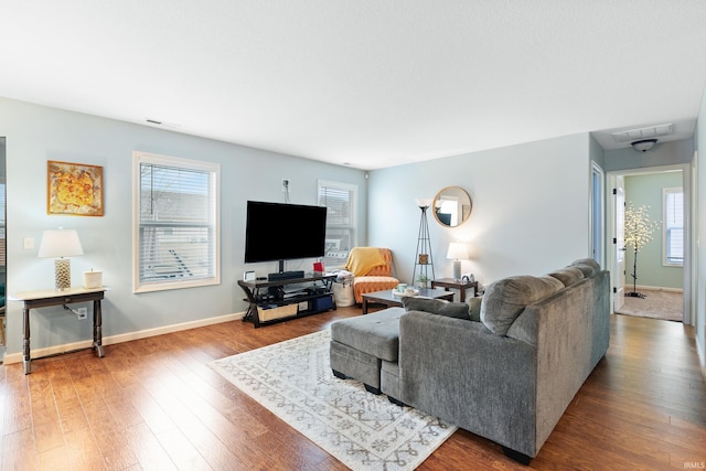 living room featuring visible vents, baseboards, and wood finished floors