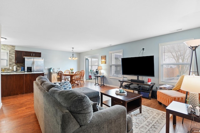 living room featuring a healthy amount of sunlight, light wood finished floors, visible vents, and a chandelier