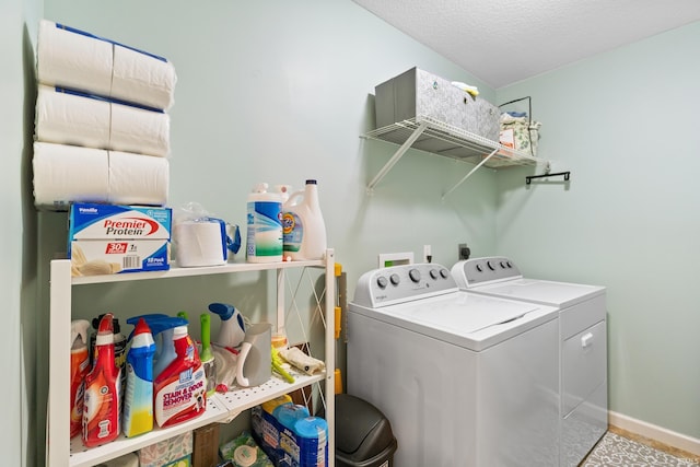 washroom featuring a textured ceiling, laundry area, washing machine and dryer, and baseboards