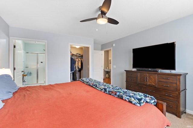 bedroom featuring a walk in closet, a closet, ensuite bathroom, a ceiling fan, and light carpet