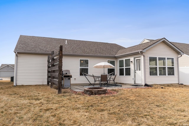 back of house with a shingled roof, a lawn, and a patio area