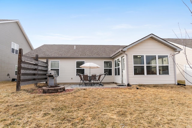 rear view of house with a patio area, a shingled roof, and a lawn