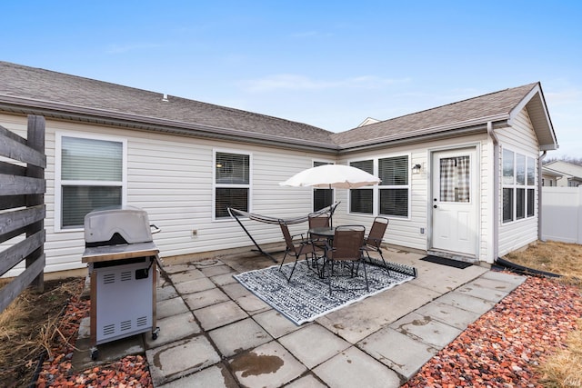 rear view of property with a shingled roof, a patio area, and fence