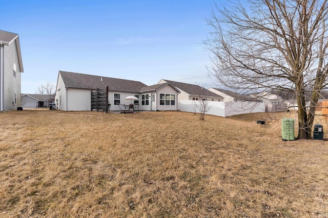 back of property featuring a lawn and fence