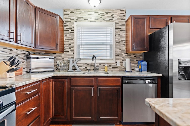 kitchen featuring stainless steel appliances, tasteful backsplash, a sink, and light stone counters