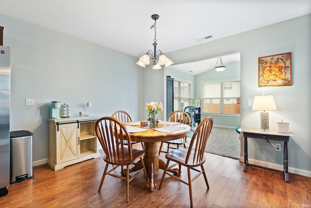 dining room with lofted ceiling, baseboards, an inviting chandelier, and wood finished floors