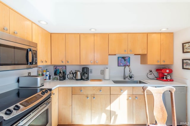 kitchen featuring appliances with stainless steel finishes, light countertops, light brown cabinets, a sink, and recessed lighting