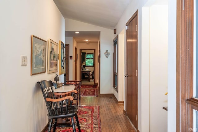 hallway with lofted ceiling, dark wood-style flooring, and baseboards