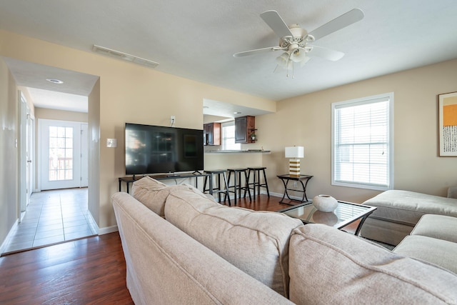 living area featuring a ceiling fan, baseboards, visible vents, and wood finished floors