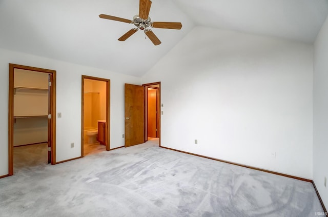 unfurnished bedroom with a closet, a spacious closet, light carpet, connected bathroom, and baseboards