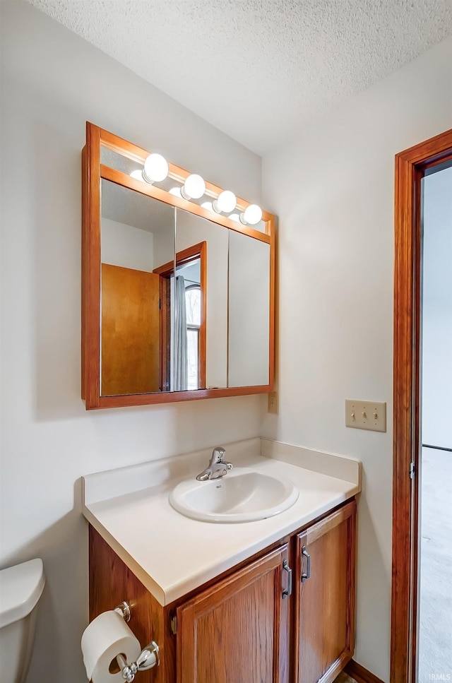 bathroom featuring a textured ceiling, toilet, and vanity