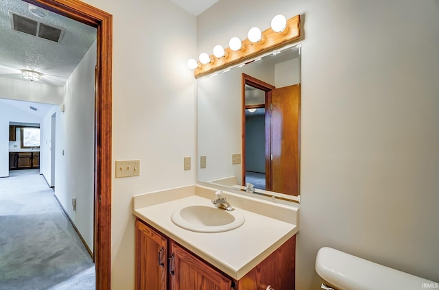 bathroom with visible vents, vanity, toilet, and a textured ceiling