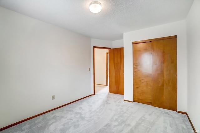 unfurnished bedroom featuring carpet, a textured ceiling, baseboards, and a closet