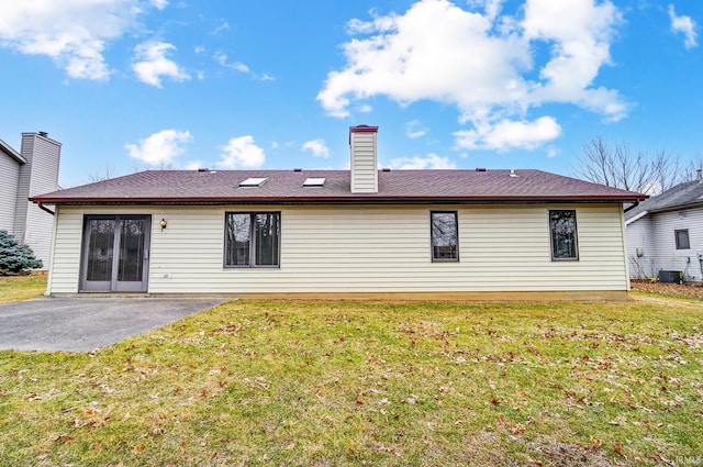 back of property featuring a patio, a yard, and a chimney