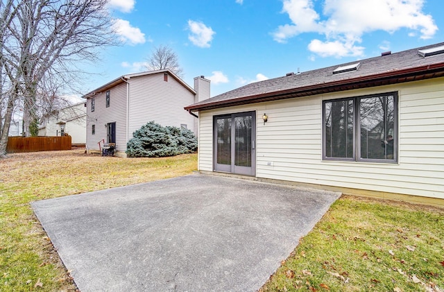 rear view of property with a chimney, a lawn, fence, and a patio