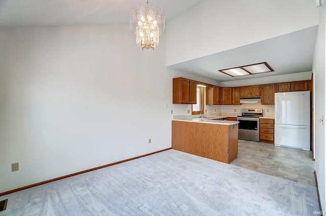 kitchen with electric stove, brown cabinets, freestanding refrigerator, a peninsula, and under cabinet range hood