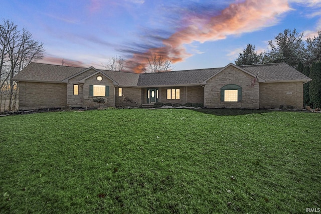 view of front facade with a lawn, brick siding, and a shingled roof