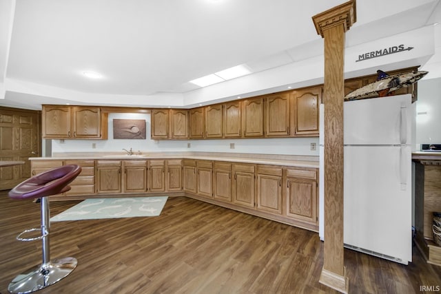 kitchen featuring brown cabinets, a sink, freestanding refrigerator, light countertops, and dark wood-style flooring