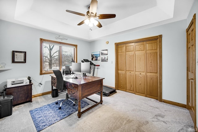 home office with carpet flooring, baseboards, a tray ceiling, and a ceiling fan