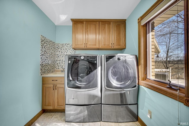 laundry area featuring baseboards, washer and dryer, light tile patterned flooring, cabinet space, and a sink