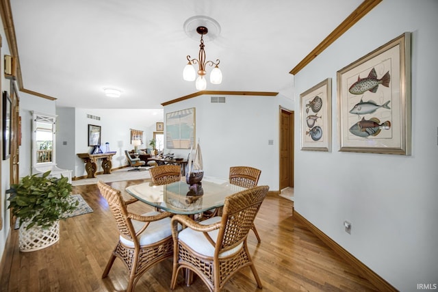 dining space with a chandelier, wood finished floors, baseboards, and ornamental molding