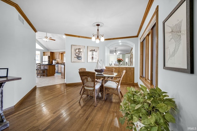 dining space with wood finished floors, baseboards, visible vents, arched walkways, and ornamental molding