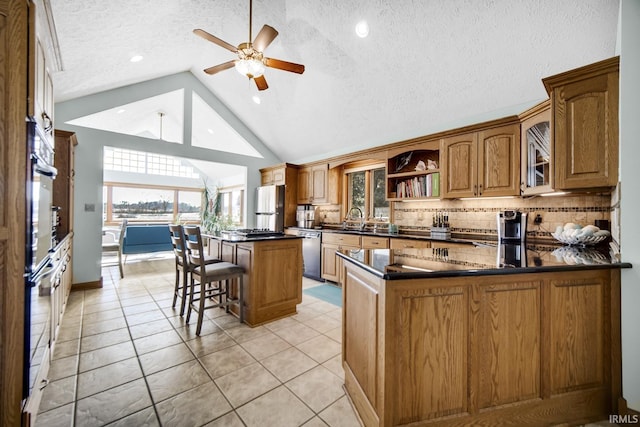 kitchen featuring dark countertops, tasteful backsplash, a breakfast bar, brown cabinets, and stainless steel appliances