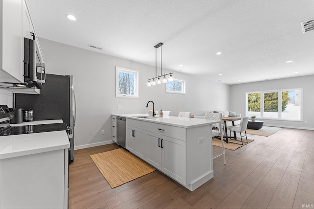 kitchen with visible vents, dishwasher, open floor plan, a peninsula, and a sink