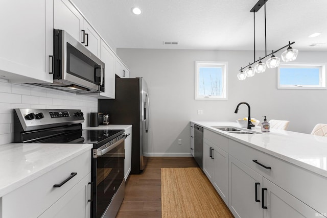 kitchen featuring visible vents, decorative backsplash, wood finished floors, stainless steel appliances, and a sink