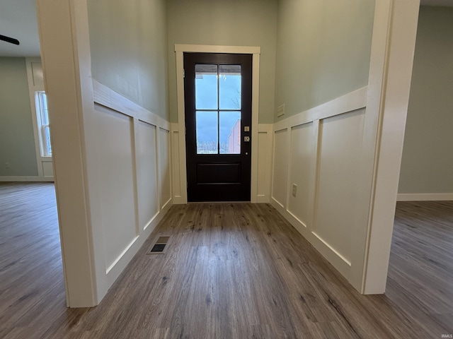 entryway with dark wood-style flooring, visible vents, a decorative wall, and wainscoting