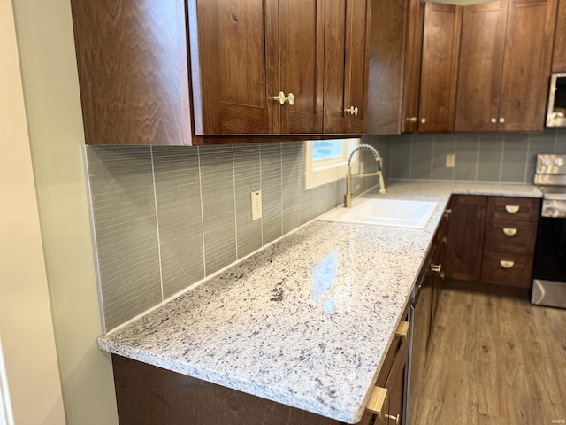 kitchen featuring light wood-type flooring, electric range, decorative backsplash, and a sink