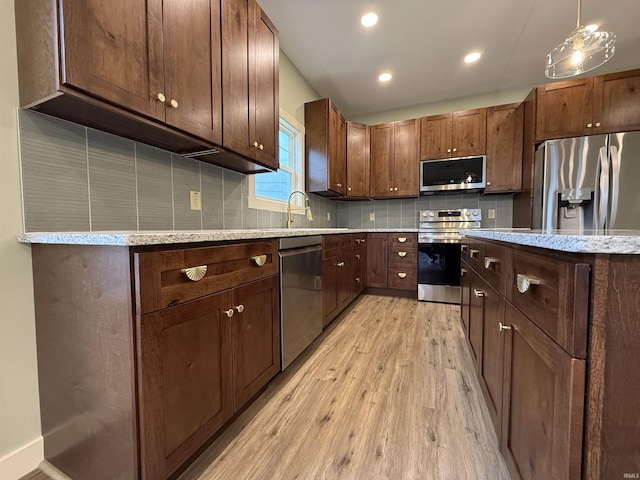 kitchen featuring decorative backsplash, stainless steel appliances, light wood-style floors, a sink, and recessed lighting