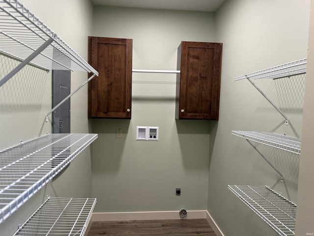 washroom with dark wood finished floors, hookup for a washing machine, cabinet space, and baseboards