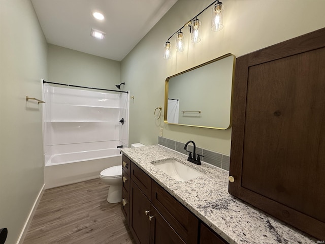 full bathroom with baseboards, toilet, wood finished floors,  shower combination, and vanity