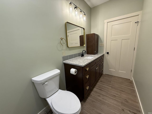 bathroom with toilet, baseboards, wood finished floors, and vanity