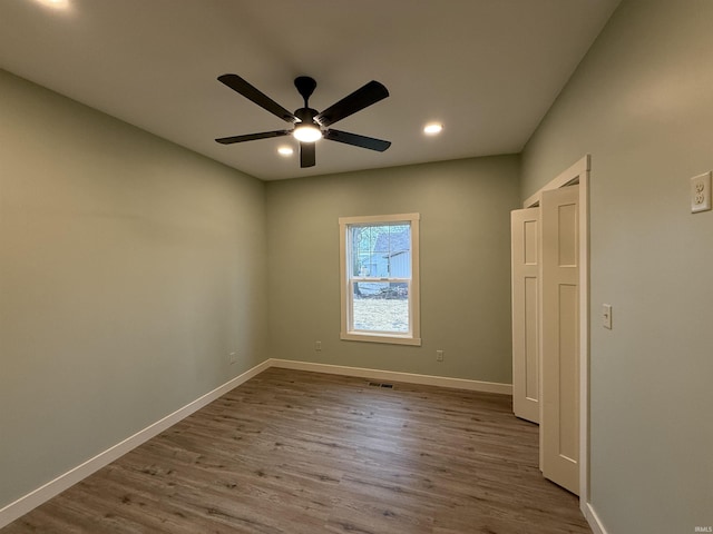 empty room with a ceiling fan, visible vents, baseboards, and wood finished floors