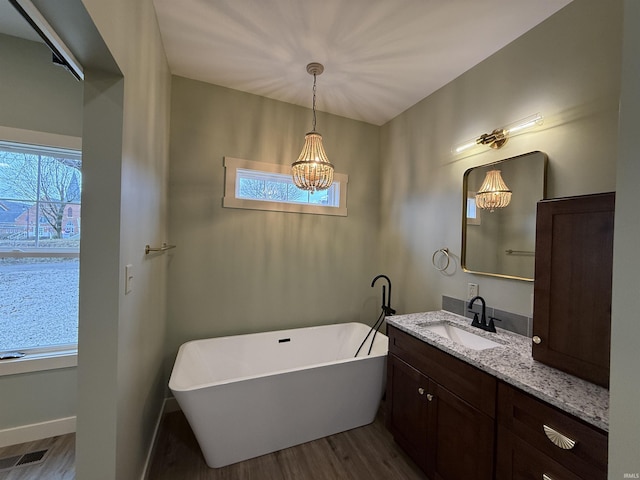 bathroom with a healthy amount of sunlight, a freestanding bath, and vanity