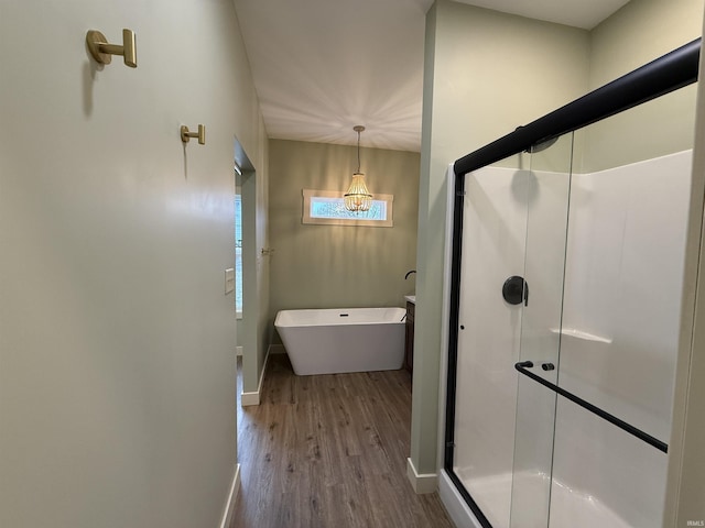 bathroom with a freestanding bath, wood finished floors, a shower stall, and baseboards