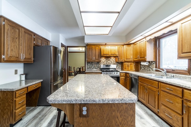 kitchen featuring a center island, stainless steel appliances, backsplash, light wood-style flooring, and a sink