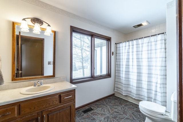 bathroom featuring toilet, vanity, visible vents, and baseboards