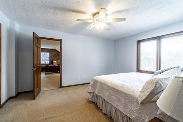 bedroom with light carpet, ceiling fan, baseboards, and a textured ceiling