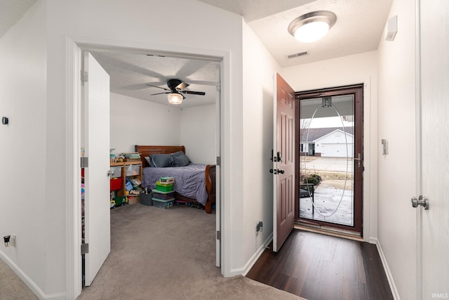 entryway featuring a textured ceiling, carpet floors, a ceiling fan, visible vents, and baseboards