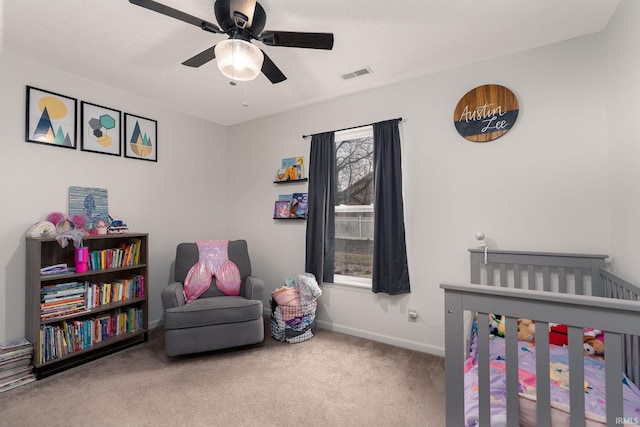 bedroom with carpet, visible vents, a ceiling fan, a crib, and baseboards