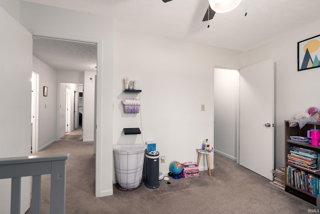 recreation room featuring a textured ceiling, ceiling fan, carpet flooring, and baseboards