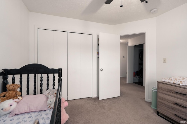 bedroom with stacked washer and clothes dryer, a closet, light carpet, ceiling fan, and a textured ceiling