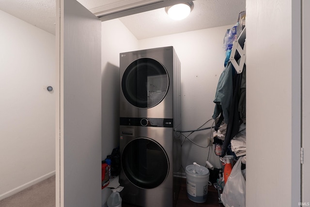 laundry room featuring carpet, stacked washer / dryer, a textured ceiling, laundry area, and baseboards