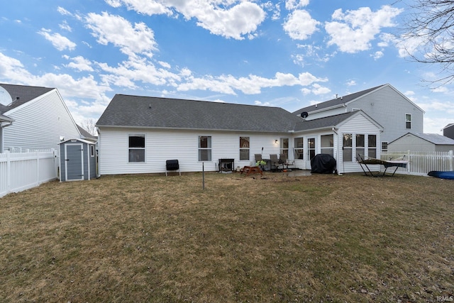 back of house with a shed, a lawn, an outdoor structure, and fence