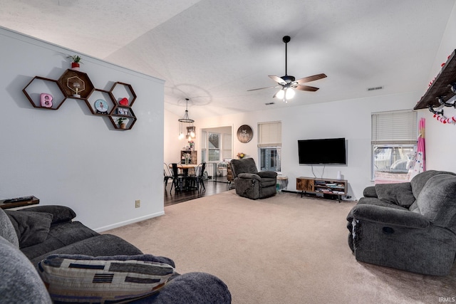 living room featuring lofted ceiling, a textured ceiling, a ceiling fan, baseboards, and carpet