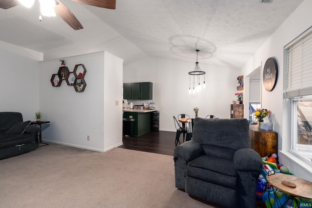 living area with a textured ceiling, ceiling fan, baseboards, vaulted ceiling, and dark colored carpet